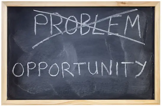 Word 'problem' crossed out on chalkboard with word 'opportunity' written underneath it