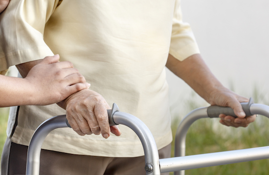 Image of senior woman using a walker with caregiver