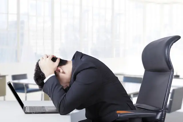 Image of stressed out employee holding his head in despair