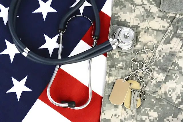 Military fatigues and dog tags on an American Flag with a stethoscope to illustrate health care in the armed services