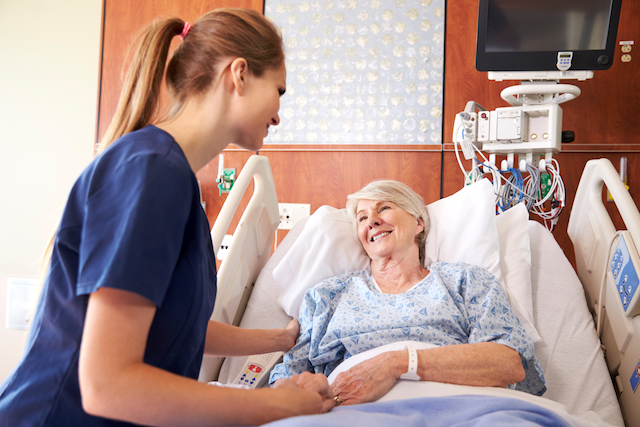 Nurse talking to senior female patient in hospital bed