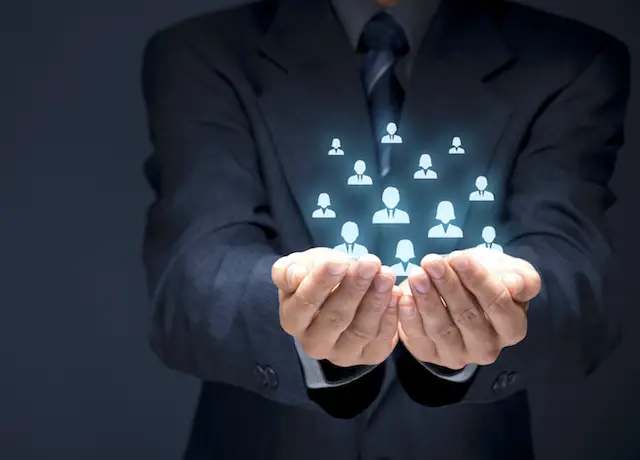 Image of businessman holding icons of people in the palms of his hands - depicts human resources concept