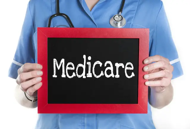 Image of nurse holding blackboard with word 'medicare' written on it