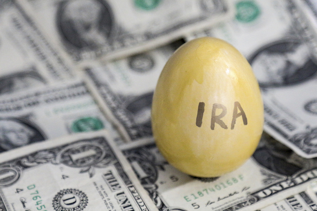 A golden egg labeled IRA is set against a background of one dollar bills.