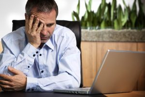 Image of businessman looking at computer with look of concern