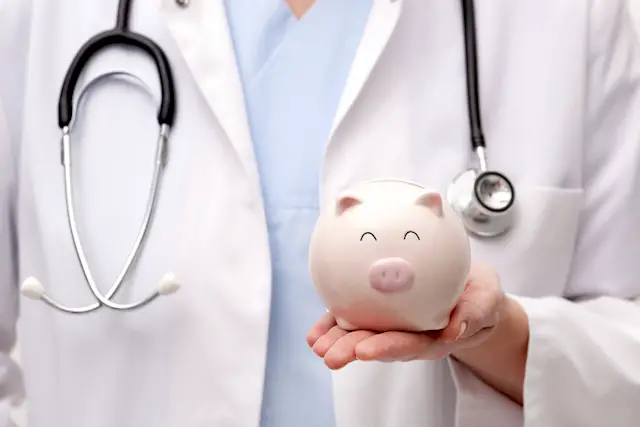 Female doctor with stethoscope holding piggy bank