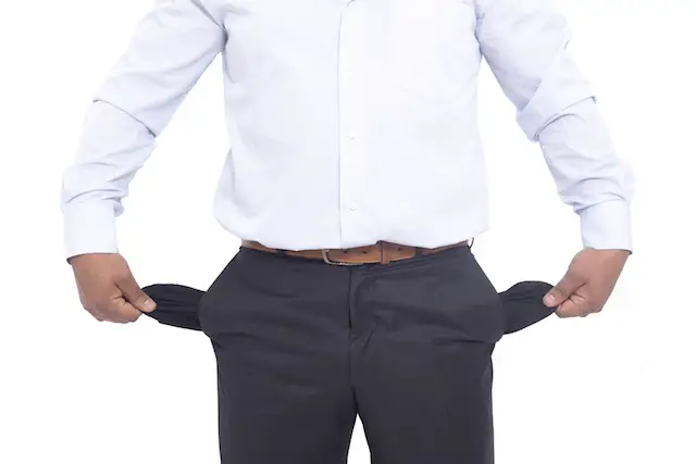 Image of a businessman pulling out his pants pocket liners to show he has no money