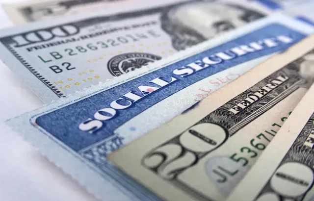Image of social security card in between several cash bills