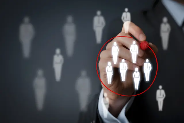 Image of a business person's hand drawing a red circle around people icons on a screen - HR concept