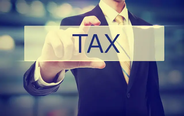 Image of business man holding the word tax against a blurred background