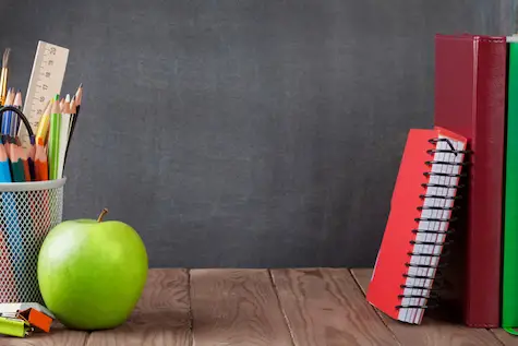 School and office supplies with an apple on a desk