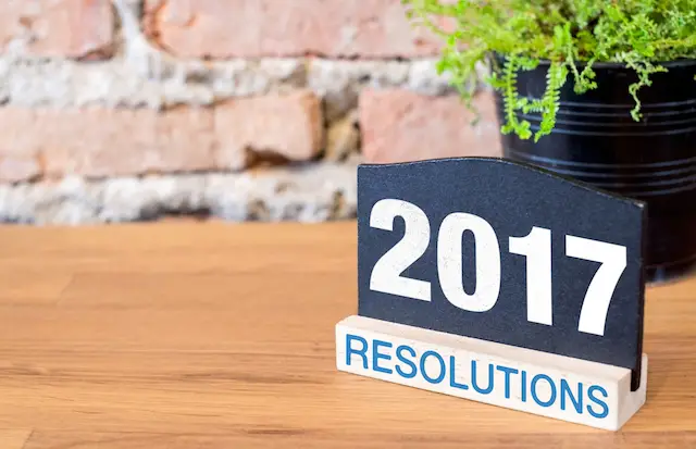 New year 2017 number on blackboard sign and green plant on wood table at brick wall