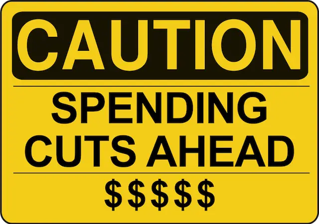 Image of a yellow caution sign that says 'spending cuts ahead'