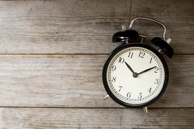 Old style alarm clock on wooden table