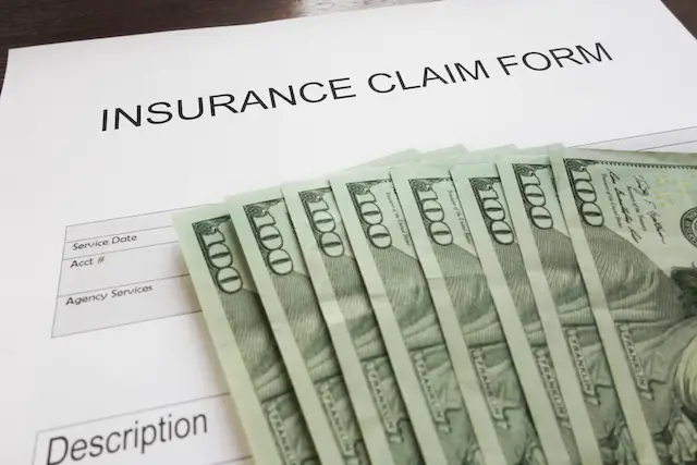 Image of health insurance claim form with a stack of $100 bills on top of it