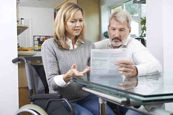 Frustrated Couple With Woman In Wheelchair Reading Letter