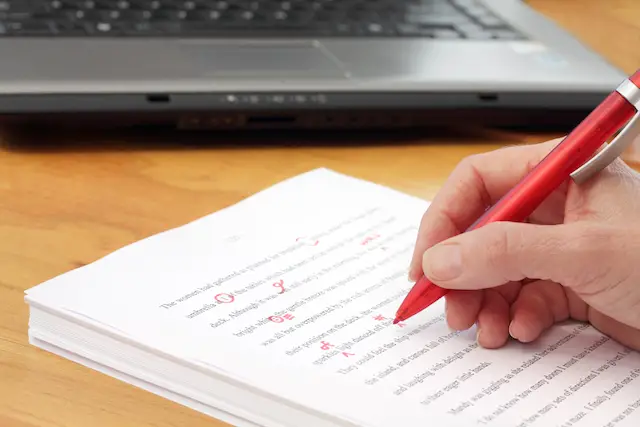 Image of a businessperson's hand proofreading a document with a red pen