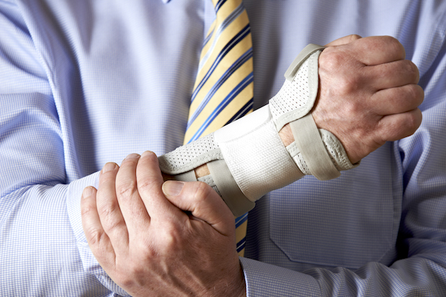 Bussinessman holding his arm in a brace with a reptitite strain injury - workplace injury, FECA