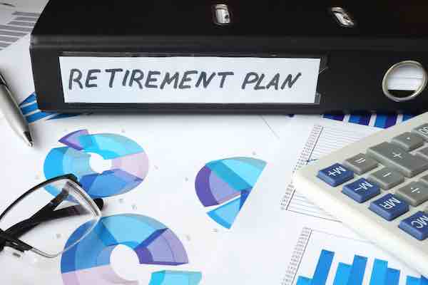 Graphs and file folder labeled 'retirement plan' on a desk