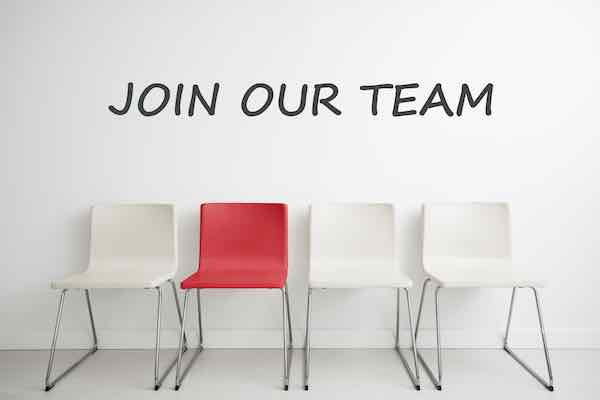 Row of four chairs, three white and one red with words 'join our team' written above