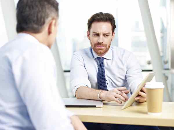 Two businessmen meeting one on one reviewing an iPad to discuss work