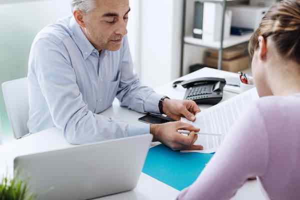 Woman meeting with a supervisor at his desk discussing an item he shows her on paperwork