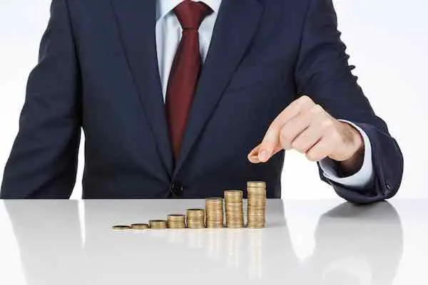 Businessman stacking coins into increasingly large individual stacks