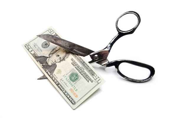 Scissors cutting a $20 bill in half
