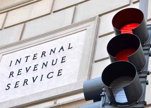 Internal Revenue Service sign with a traffic signal in the foreground indicating a red light