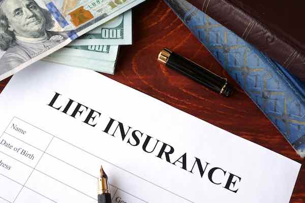 Life insurance policy application and currency on a table