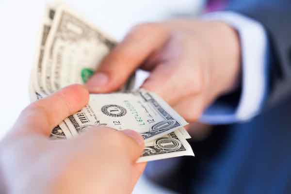 Closeup of business man giving bank notes to another person