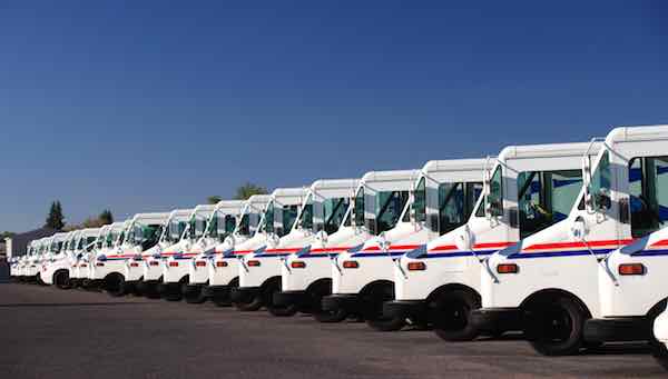 A fleet of US postal service vehicles parked in a line
