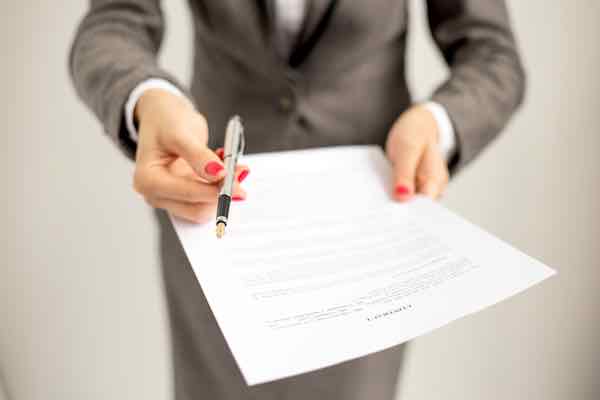 Businesswoman holding a contract letter and a pen as a gesture to have somebody sign it