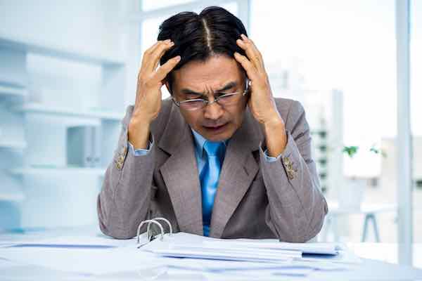 Worried businessman working at his desk in office staring at an open binder