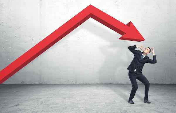 Businessman standing on the floor in a desperate pose under the giant red arrow representing financial loss aiming down at him