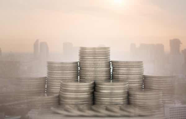 Stacks of coins in foreground against a city skyline