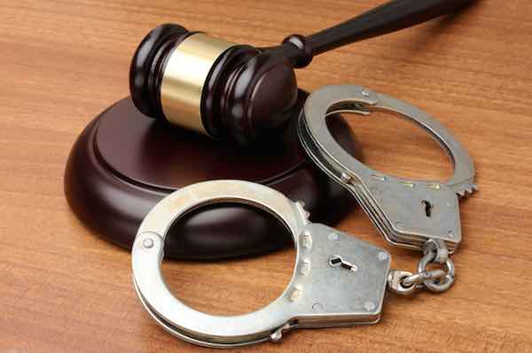 Handcuffs with gavel on a wood background