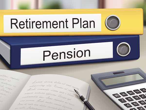 retirement plan and pension binders on a desk with a calculator and notepad