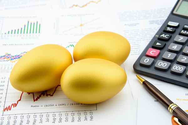 Three golden eggs with a calculator on business and financial reports