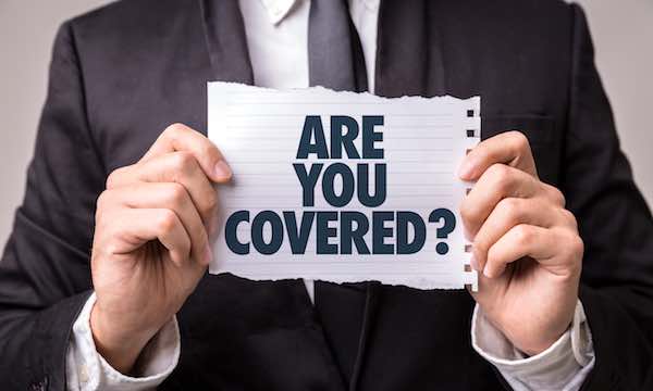 Businessman holding a sheet of paper that says 'Are you covered?'