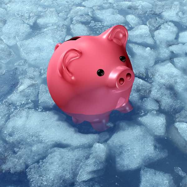 Piggy bank sitting in a pool of water surrounded by chunks of ice