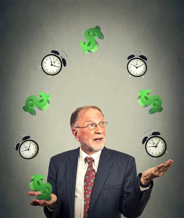 Senior businessman in suit juggling multiple alarm clocks and dollar signs