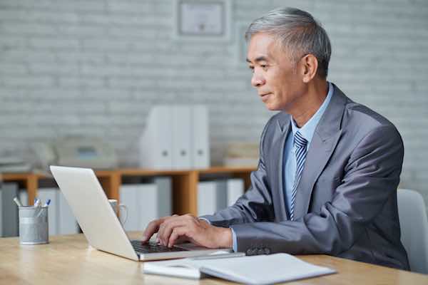 Retirement age man in business suit working on a computer