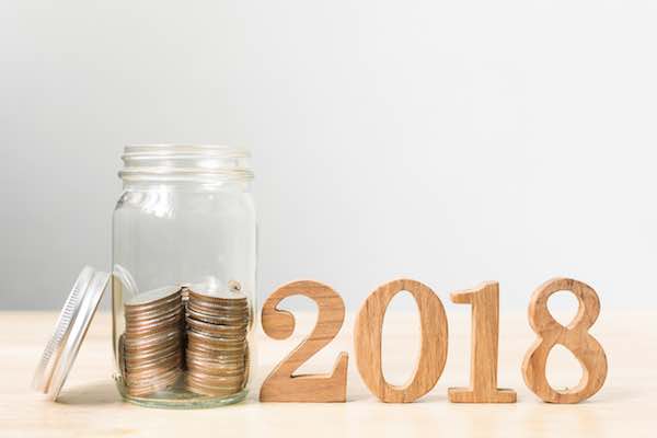 Coins in a jar next to wooden numbers reading '2018'