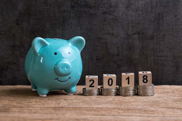 Blue piggy bank next to the numbers '2018' on a rising stack of coins indicating a pay raise for the new year