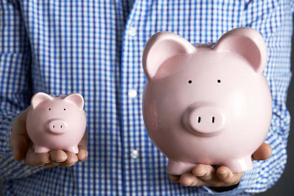 Man holding large and small piggy bank symbolizing a large versus small pay raise