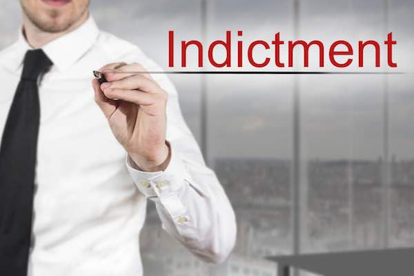 businessman in office writing the word 'indictment' on a screen