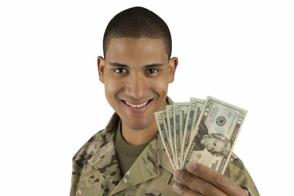 Male soldier wearing camouflage smiling as he holds cash in his hand