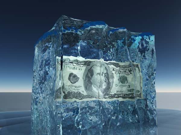 $100 bill frozen inside a block of ice indicating a pay freeze