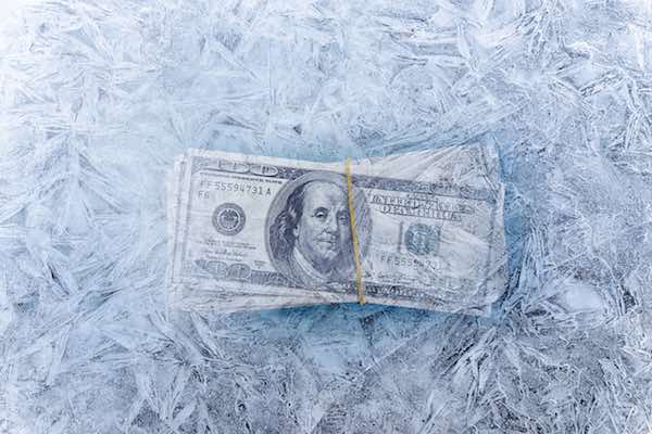 Hundred dollar bills in ice signifying a pay freeze